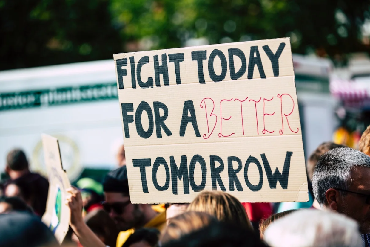 peple protesting holding a sign that says fight for a better tomorrow